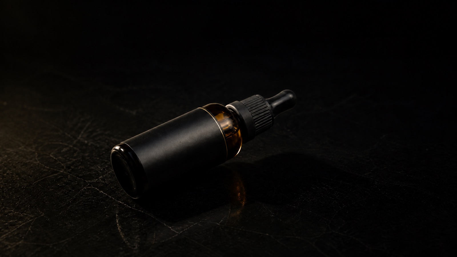 Beard Oil — seen in three-quarter view, low in a wide frame — under a single warm gold light on black.