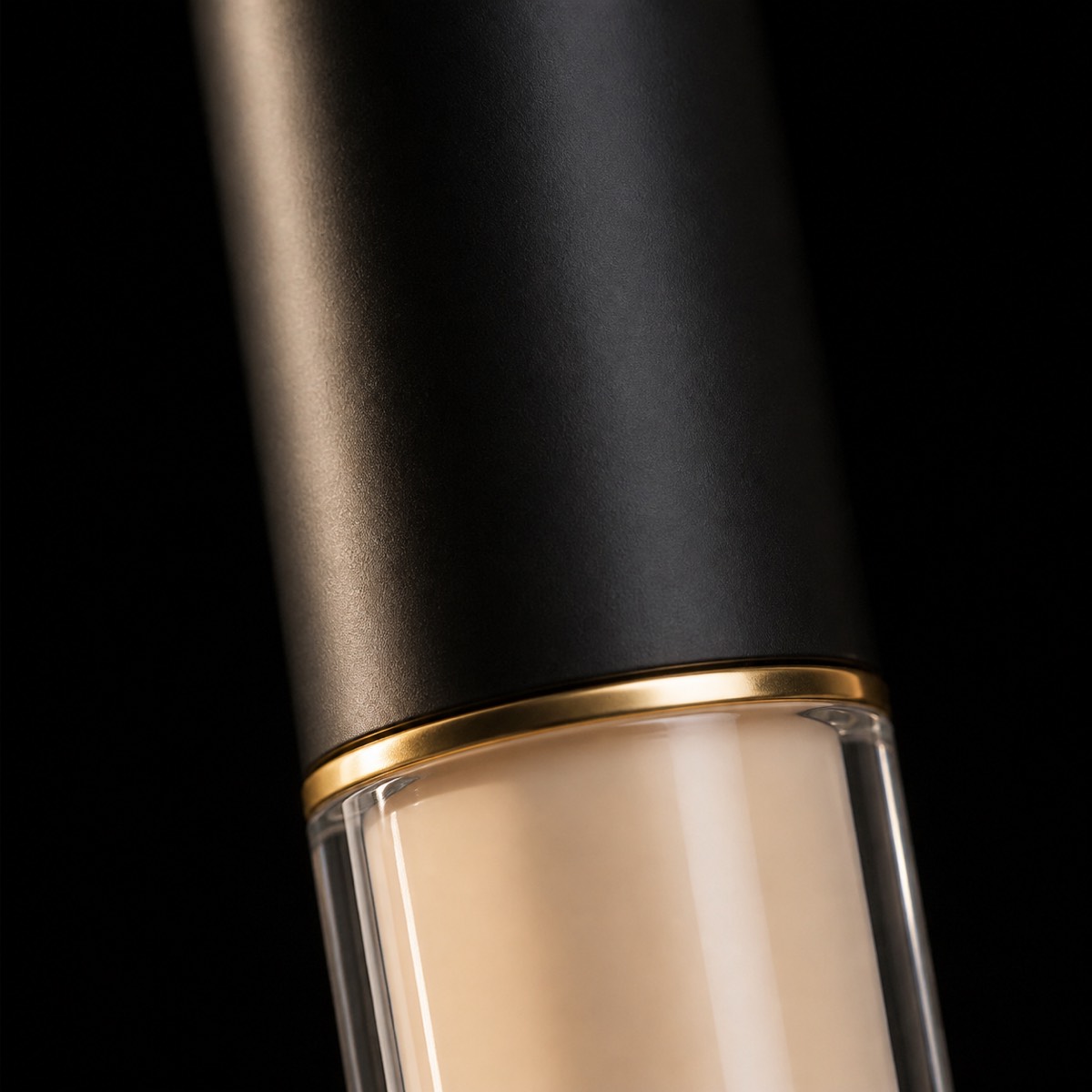 Concealing Cream — the working end at magnification — under a single warm gold light on black.