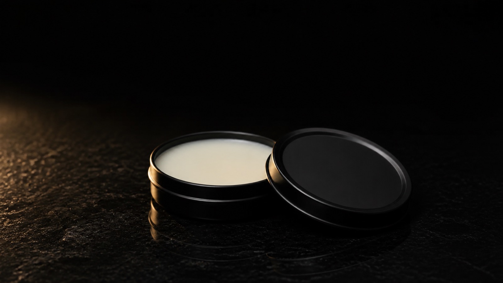 Solid Fragrance — seen in three-quarter view, low in a wide frame — under a single warm gold light on black.