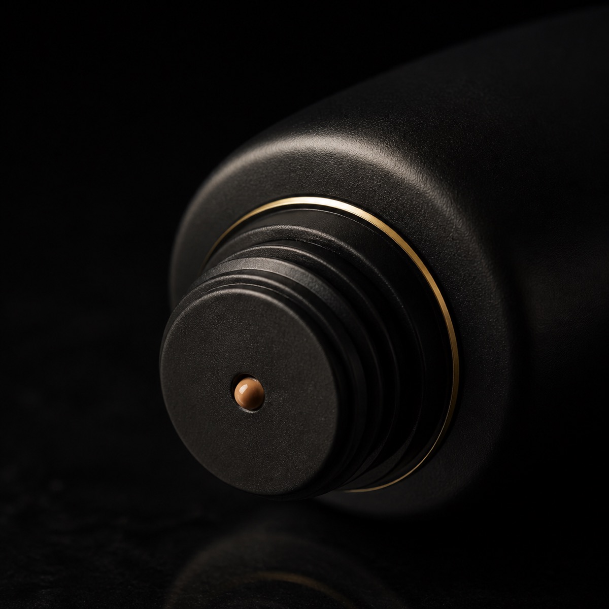 Bronzing Moisturizer — the working end at magnification — under a single warm gold light on black.