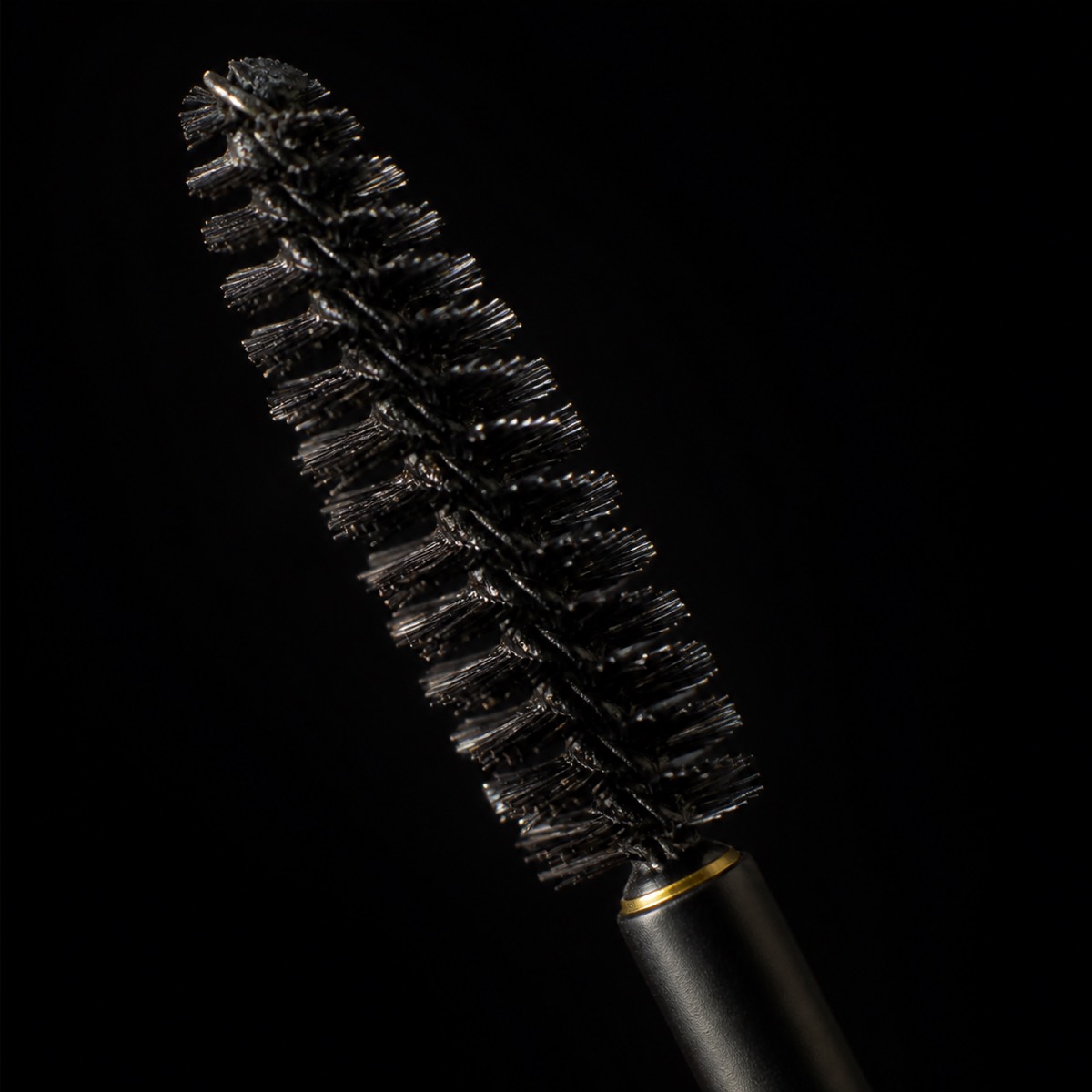 Brow Soap — the working end at magnification — under a single warm gold light on black.