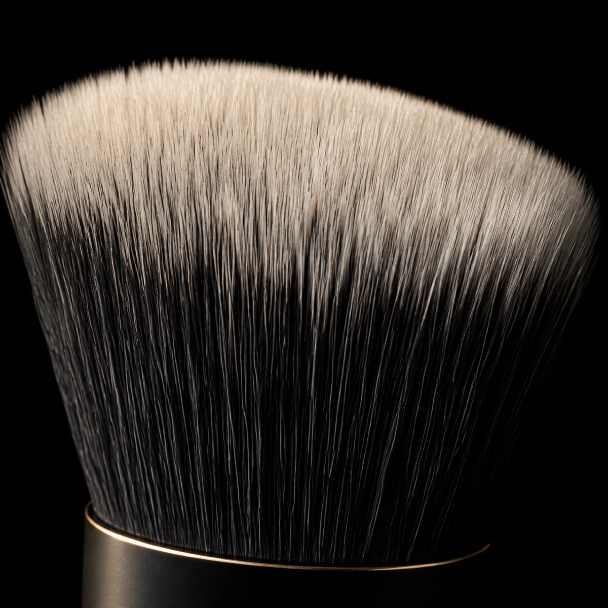 Stipple & Blend Brush — the working end at magnification — under a single warm gold light on black.