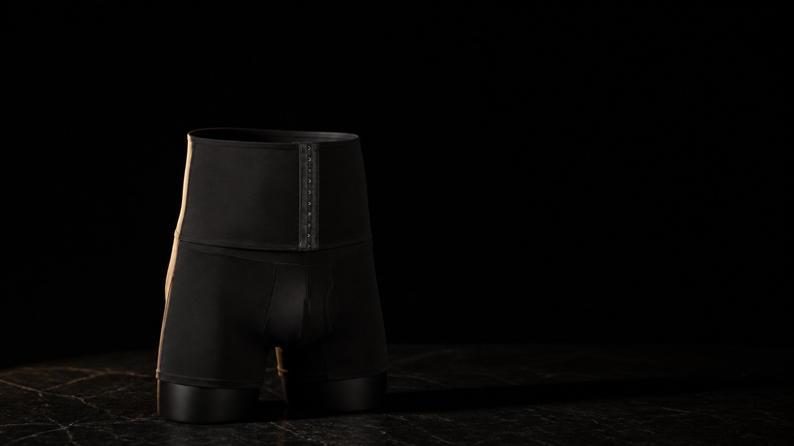 High-Waist Shaping Short — Men's Cut — seen in three-quarter view, low in a wide frame — under a single warm gold light on black.