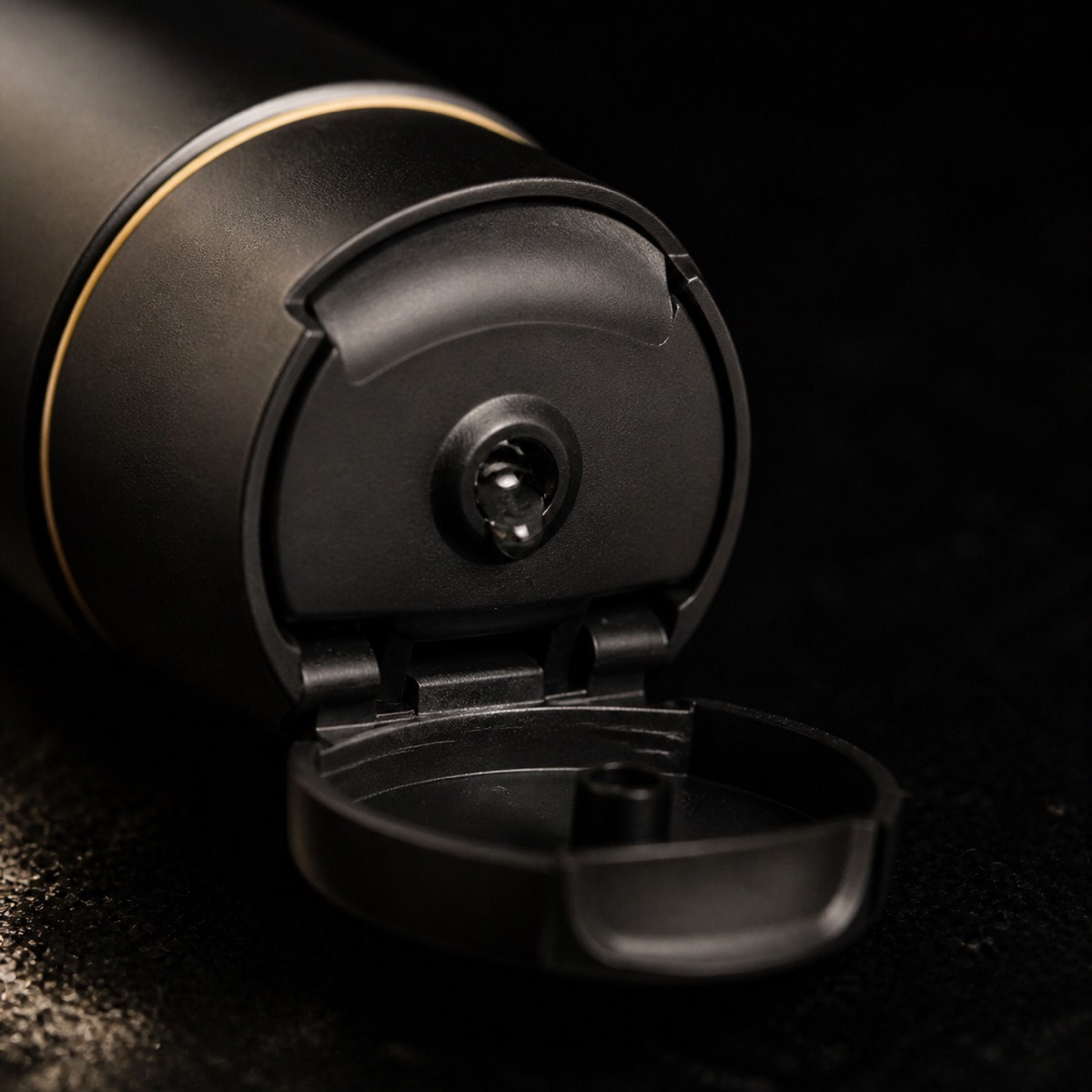 Charcoal Facial Cleanser — the working end at magnification — under a single warm gold light on black.