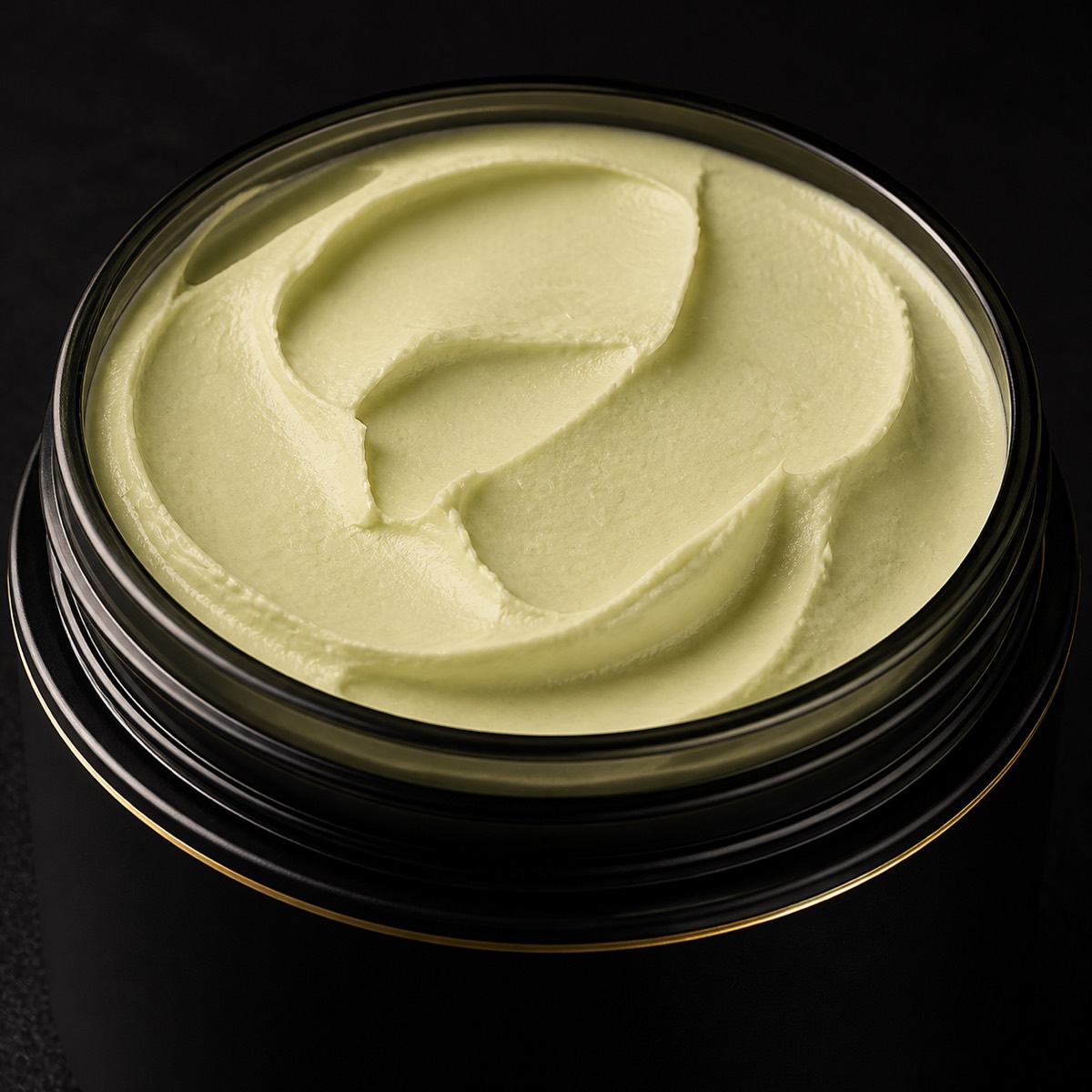 Raw Shea Butter — the working end at magnification — under a single warm gold light on black.
