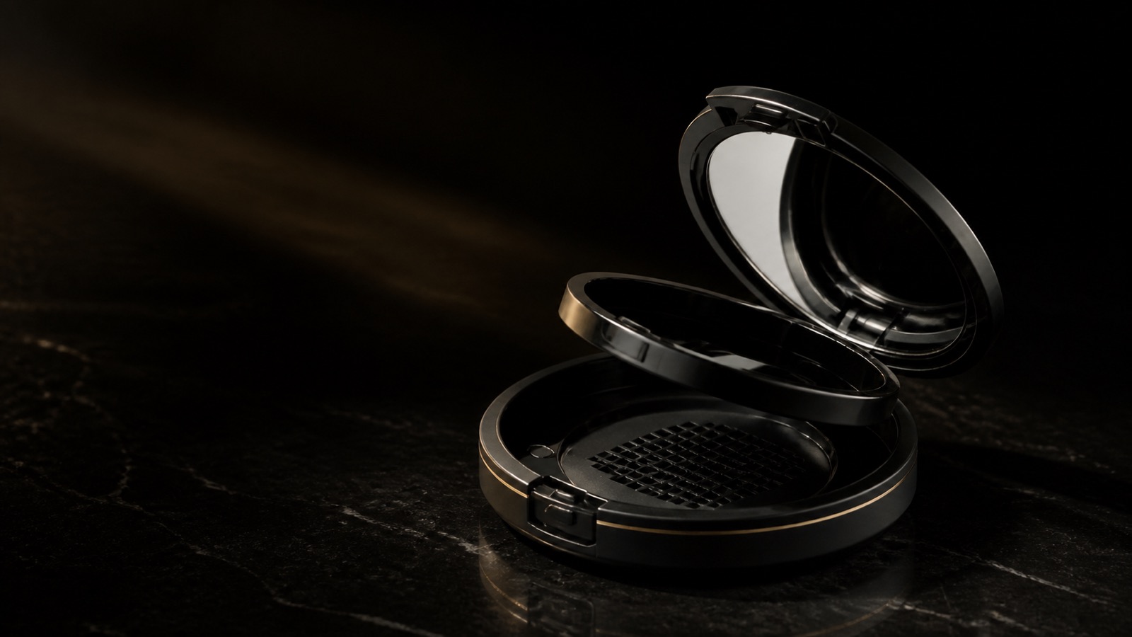 Compact Mirror — seen in three-quarter view, low in a wide frame — under a single warm gold light on black.
