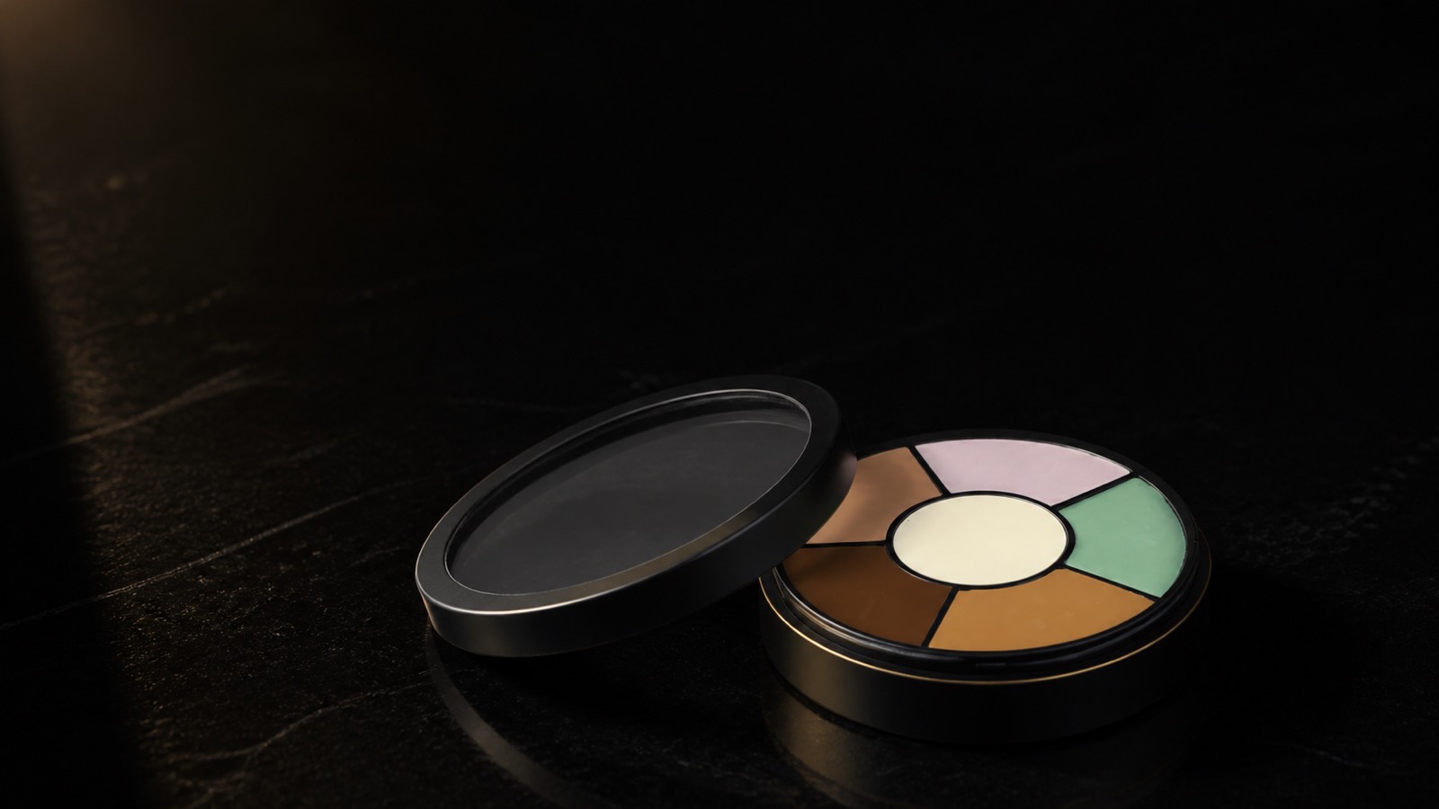 Corrector Wheel — Six Tones — seen in three-quarter view, low in a wide frame — under a single warm gold light on black.