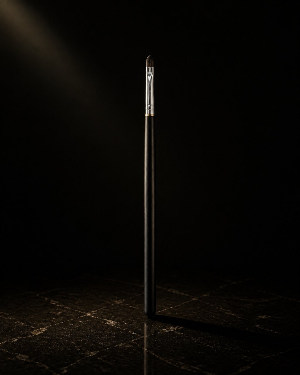 Oval Lip Brush — oval lip brush — standing alone against near-black under a single warm gold light.