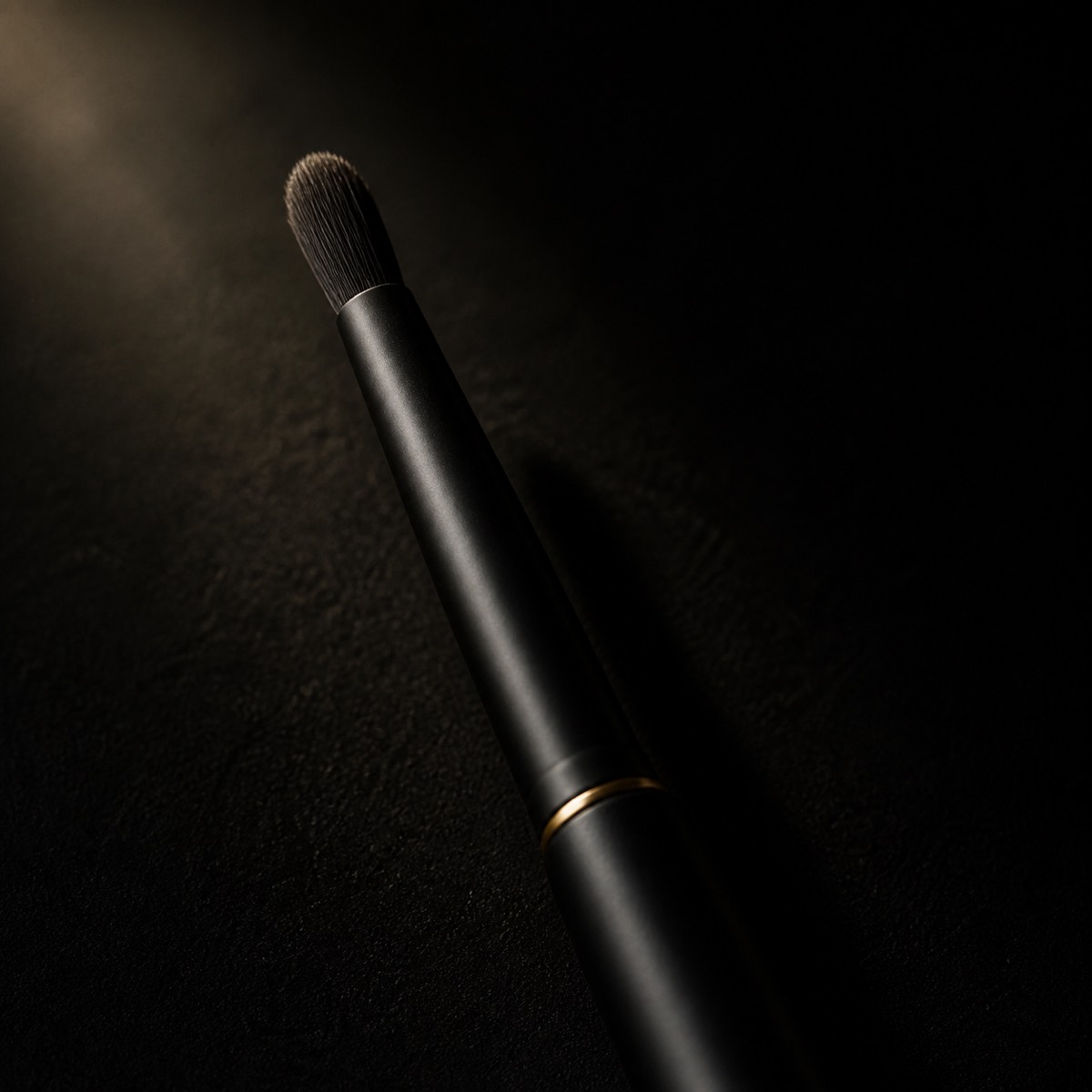 Small Detail Brush — the working end at magnification — under a single warm gold light on black.