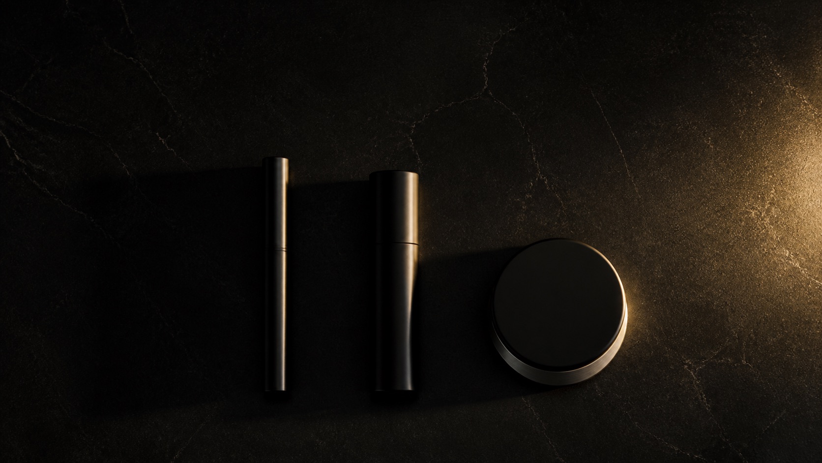 Three objects laid flat in one row on black lacquer, seen from above, each holding a single gold edge.