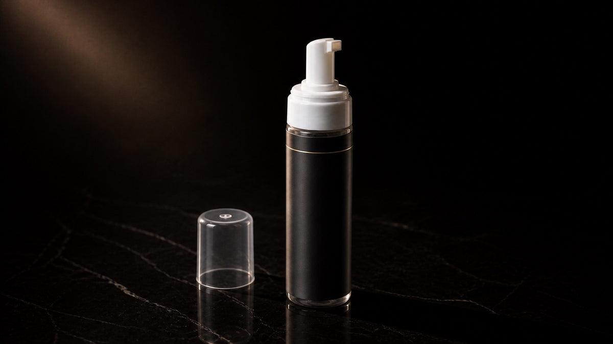 Bounce Boost Mousse — seen in three-quarter view, low in a wide frame — under a single warm gold light on black.