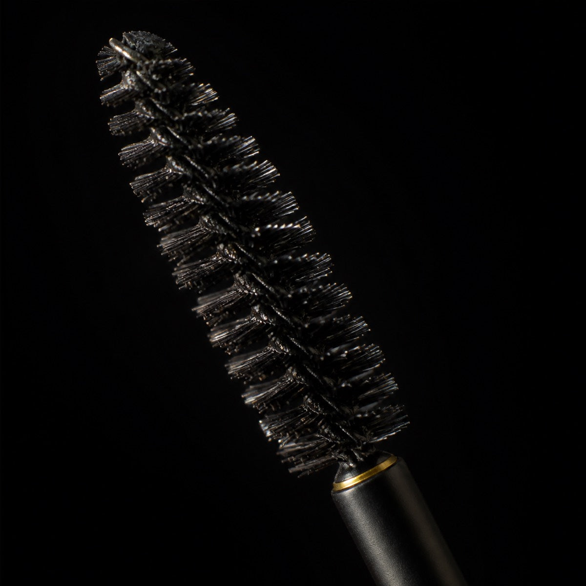 Brow Soap — the working end at magnification — under a single warm gold light on black.