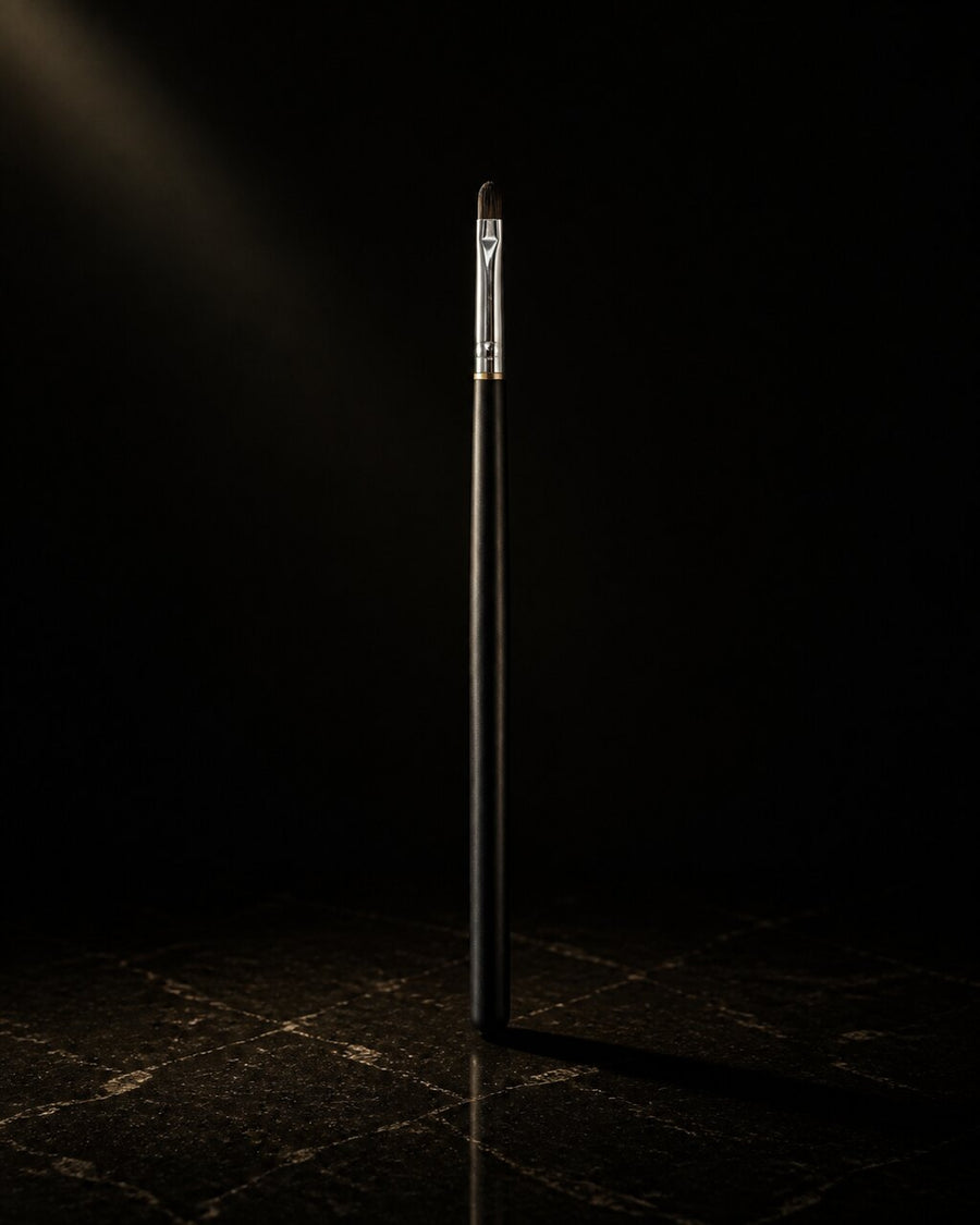 Oval Lip Brush — standing alone, complete — under a single warm gold light on black.