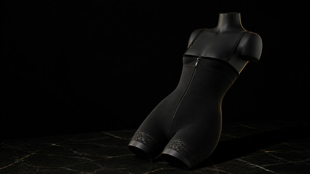 Under-Bust Zip Bodysuit — seen in three-quarter view, low in a wide frame — under a single warm gold light on black.